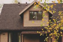 brown house faded in background with fall tree in foreground