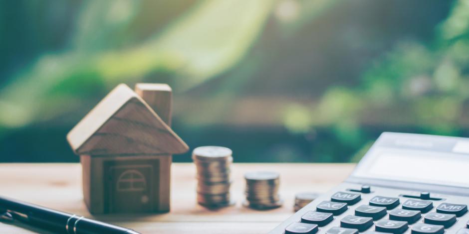 model house with calculator, coin stacks and pen with green tree background, home financing concept